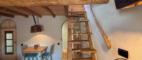 A wooden interior with a staircase, a dining area, and a view of the outside.