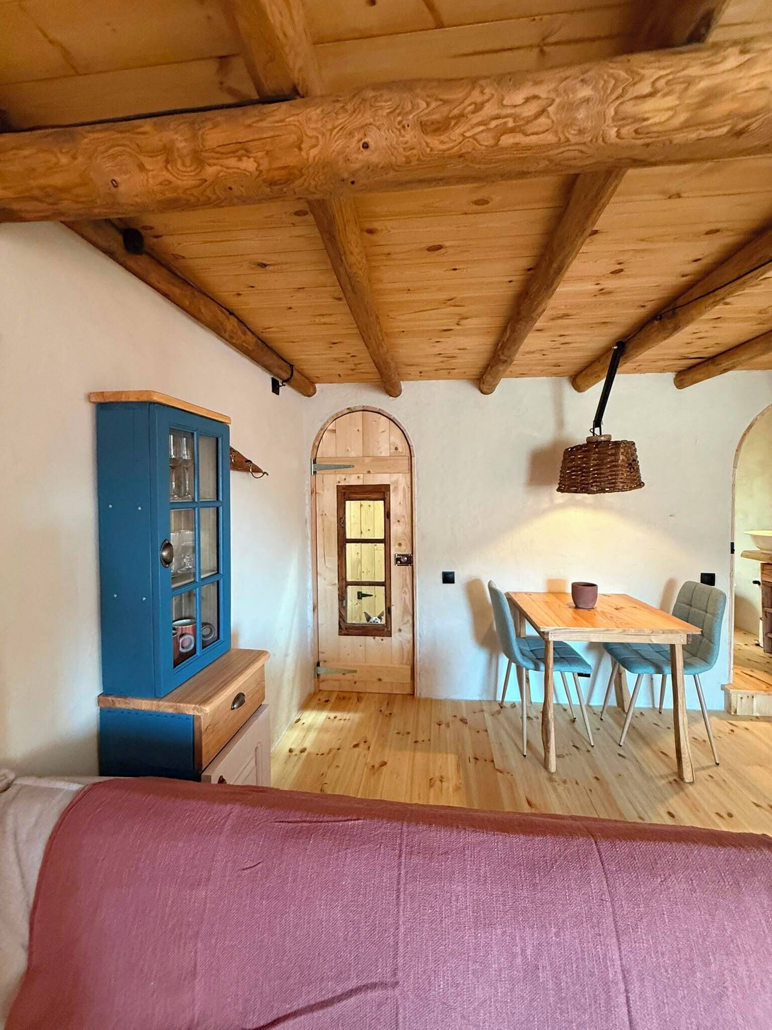 A wooden interior with a dining table, chairs, a cabinet, and a door.