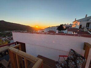 A balcony with a wooden railing, a wooden chair, and a floral-patterned cushion. - A home you'll want to stay in, with a terrace overlooking the mountains and the village (Castelo de Vide)
