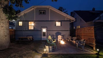 A two-story house with a patio area featuring outdoor seating and a fire pit.