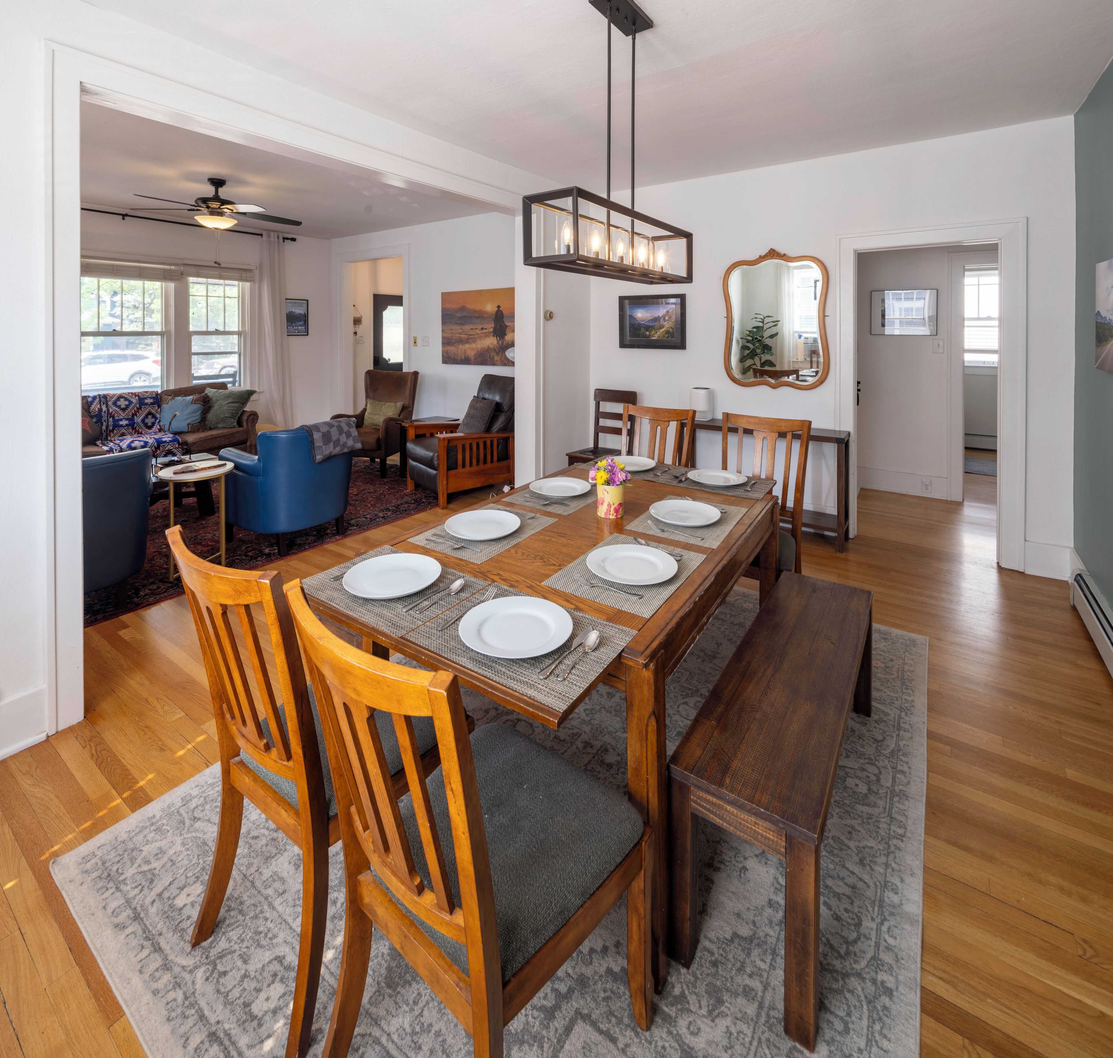 Un coin repas avec une table en bois dressée pour six personnes, entourée de six chaises.