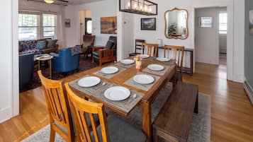 Un coin repas avec une table en bois dressée pour six personnes, entourée de six chaises.