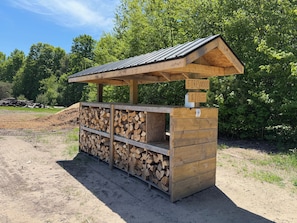 Estructura de madera con techo, etiquetada como 'Firewood' y con un precio de 10 dólares por pie cúbico.