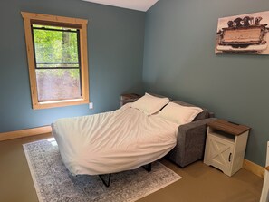 Une chambre à coucher comprenant un lit, une fenêtre, une table de chevet, une armoire et un tableau accroché au mur.