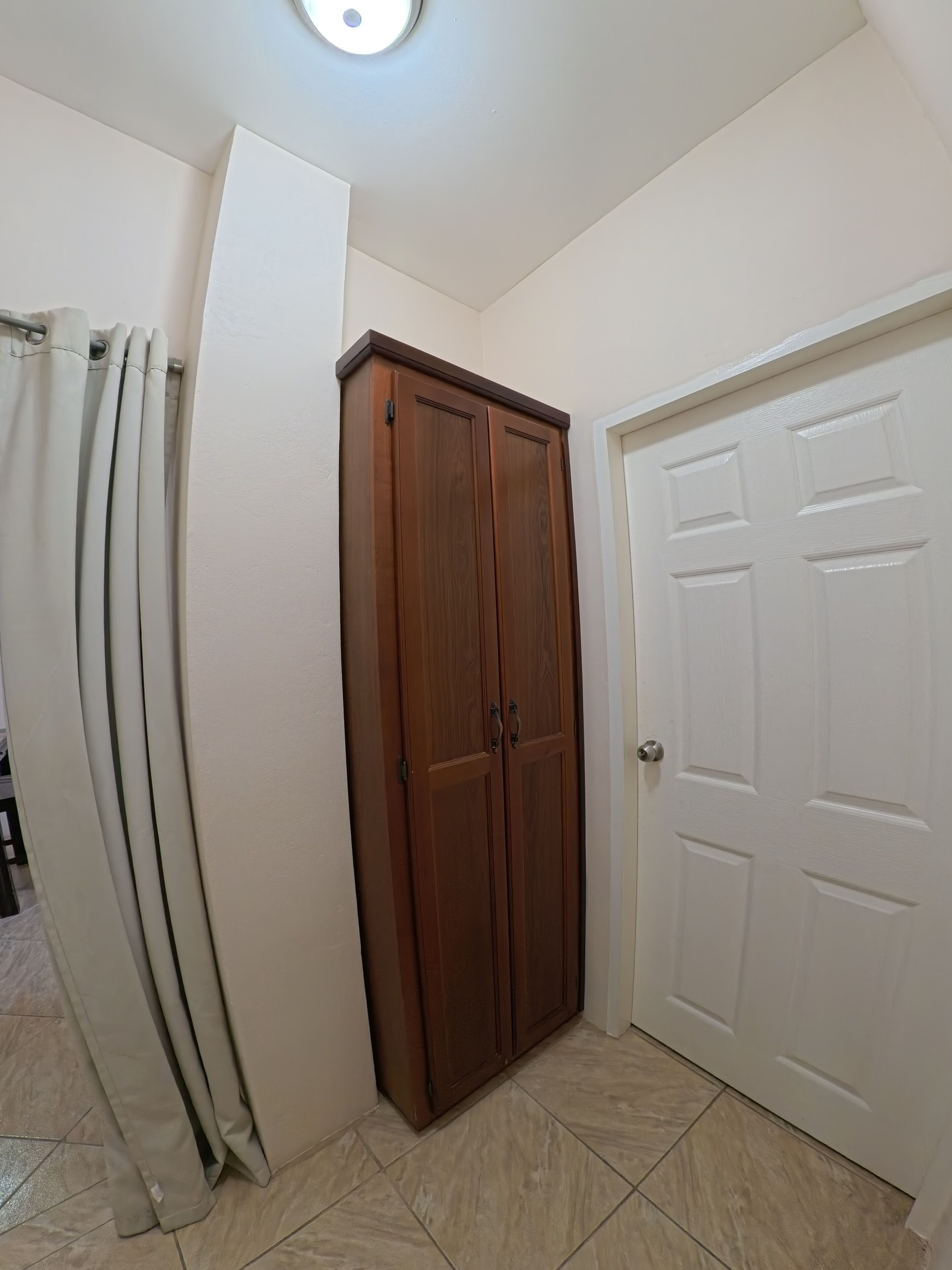 Una habitación con armario, puerta y cortina.