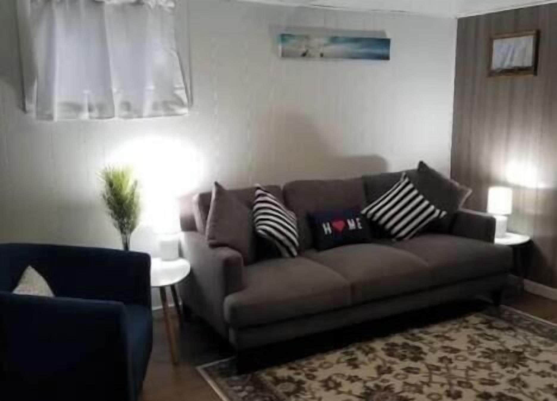 A living room with a sofa, two side tables, a lamp, and a rug.