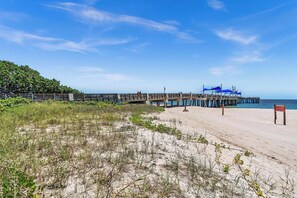 A beach with a wooden pier extending into the water, a sandy area with sparse vegetation, and a clear blue sky. - Pompano Beach + Townhouse + Private Beach + 3 bedroom + Pool = PERFECTION! (Pompano Beach)