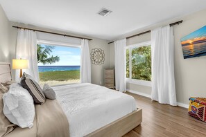A bedroom with a large bed, a nightstand, a dresser, and a window with a view of the beach and ocean. - Pompano Beach + Townhouse + Private Beach + 3 bedroom + Pool = PERFECTION! (Pompano Beach)
