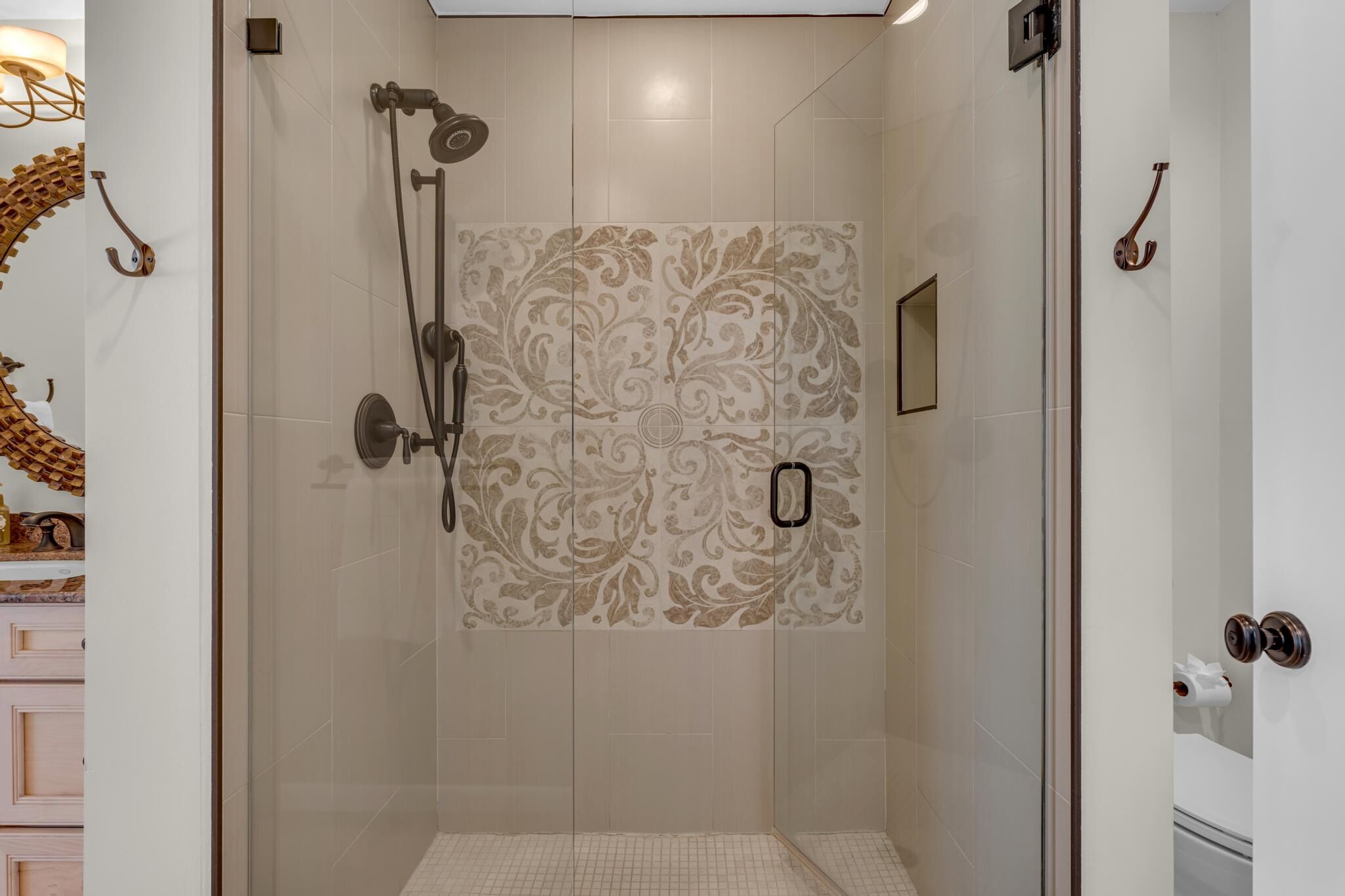 Une salle de bain moderne dotée d’une douche à parois de verre, de carreaux muraux à motifs et d’un design minimaliste.