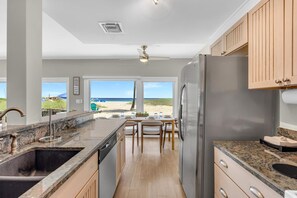 Une cuisine moderne avec vue sur la plage, un coin repas et un réfrigérateur.