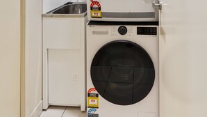 Uma lavanderia compacta com máquina de lavar e secar frontal, uma pia pequena e um armário.