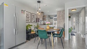 Una cucina moderna con zona pranzo, che include un frigorifero, un piano cottura e un tavolo da pranzo con sedie.