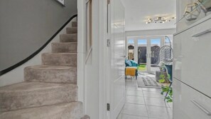 A staircase leading to a room with a view of a garden and outdoor seating area. - Fully Furnished 3 Bed House-Blythe Valley Park Shirley B90 8AY (Shirley Solihull)