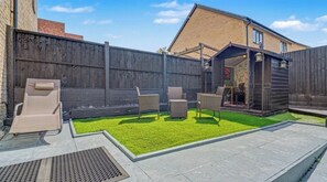 A backyard with a patio area, a wooden fence, and a small shed. - Fully Furnished 3 Bed House-Blythe Valley Park Shirley B90 8AY (Shirley Solihull)