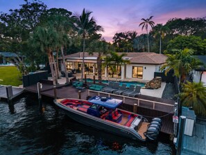 A waterfront property with a dock, a boat, and a pool area. - Mega-Yacht Showcase Villa with Pool Table/Marble (Fort Lauderdale)