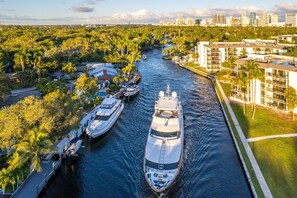 Un port de plaisance où sont amarrés plusieurs yachts, entouré d’une végétation luxuriante et de bâtiments modernes.
