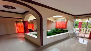 Um quarto amplo com uma grande janela, uma mesa de recepção e vista para o exterior.