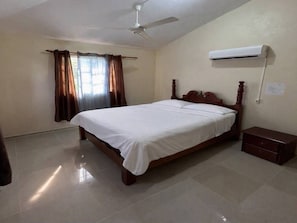 Ein Schlafzimmer mit einem Bett, Deckenventilator, Klimaanlage und Nachttisch.