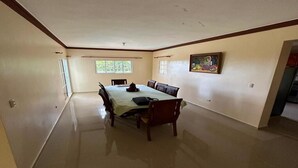 Um quarto espaçoso com uma mesa de jantar, cadeiras, uma janela e um quadro na parede.