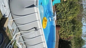 Une piscine dotée d’un système de filtration, entourée d’une pelouse et d’arbres.