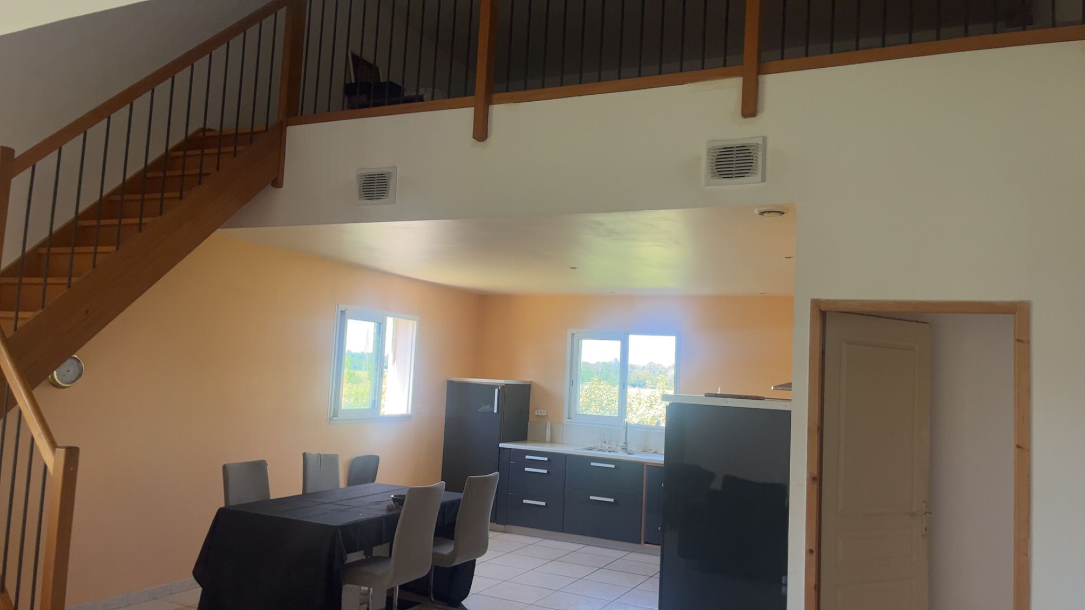 A dining area with a table and chairs, a kitchen with cabinets, and a staircase.