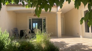 Un espace extérieur aménagé en terrasse, avec une table et des chaises, une porte et une vue sur le paysage environnant.