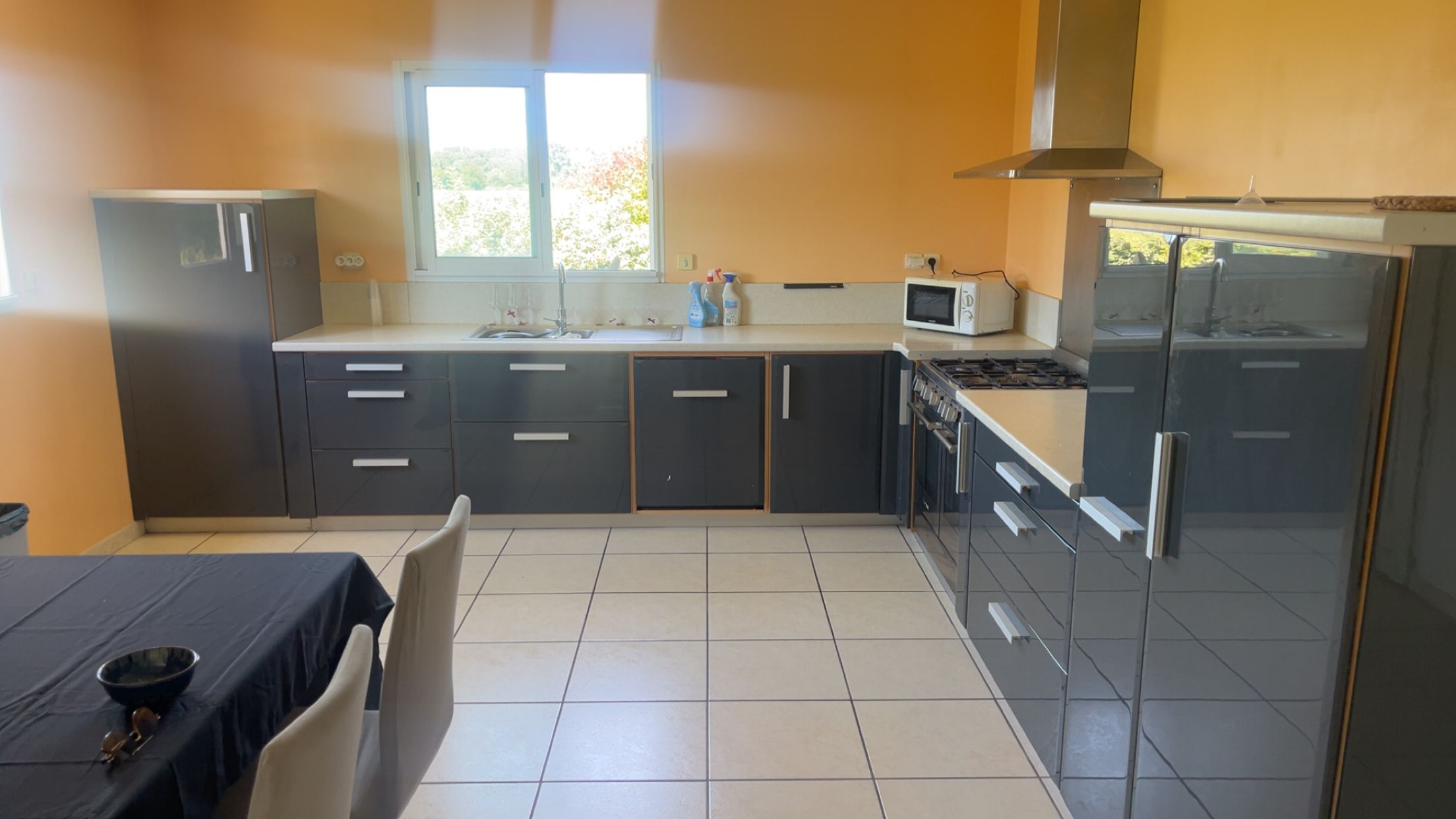 Une cuisine avec une fenêtre, un four à micro-ondes, une cuisinière et des placards.