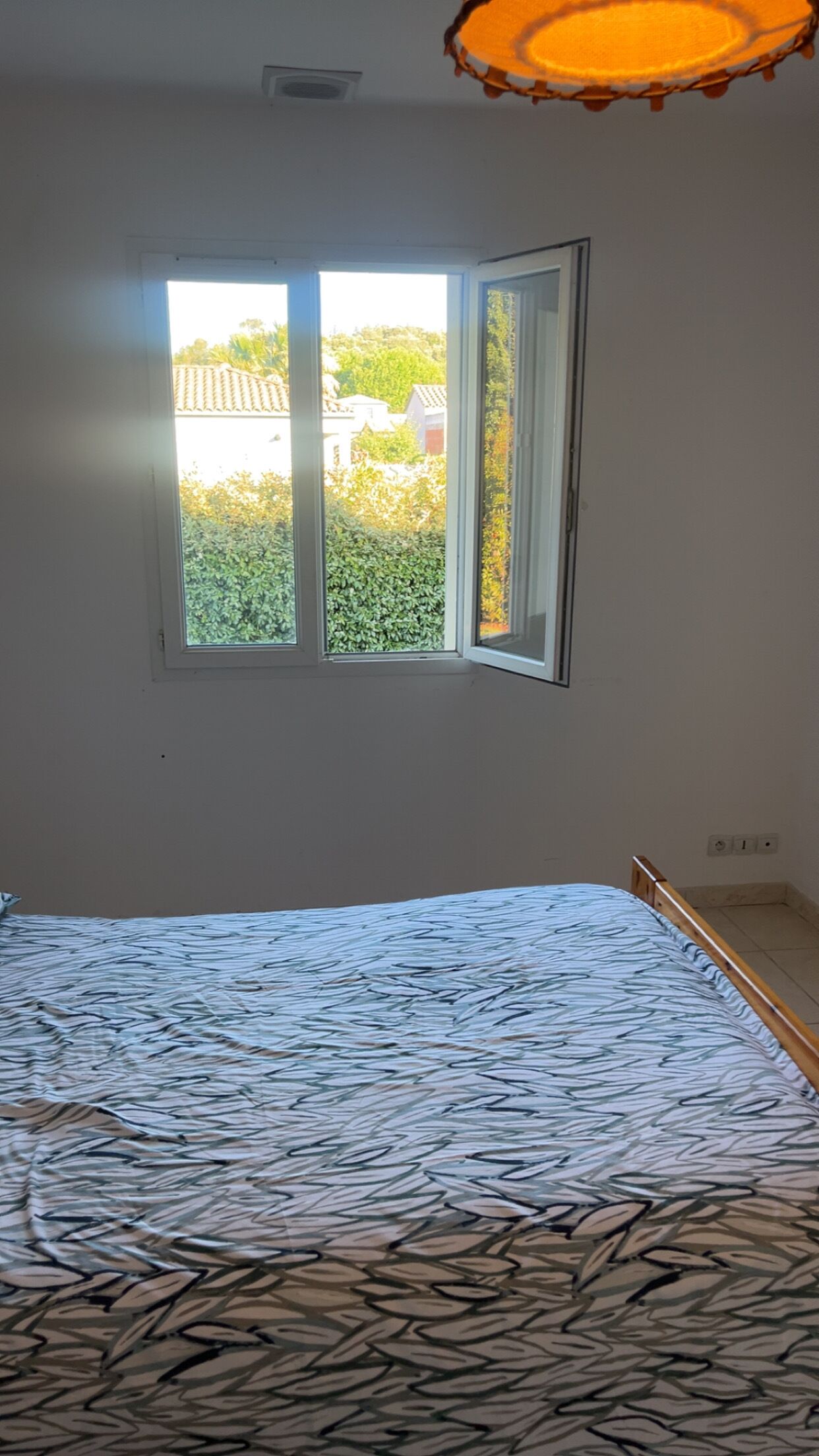 A bedroom with a bed, a window, and a ceiling light fixture.