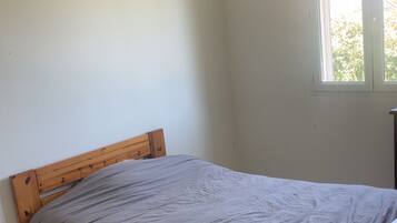 A room with a single bed, a window, and a hanging light fixture.