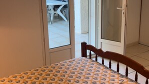 Une pièce comprenant un lit, une porte donnant sur un espace extérieur et une chaise visible à travers la porte.