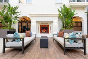 A modern outdoor seating area with two sofas, a central coffee table, and a fireplace.