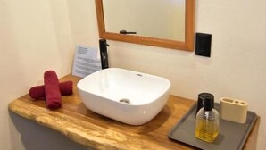 Une salle de bain avec un meuble-lavabo en bois, un lavabo blanc, un miroir et un porte-serviettes.