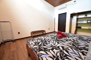 A bedroom with a bed, a bench, a wardrobe, and a radiator.