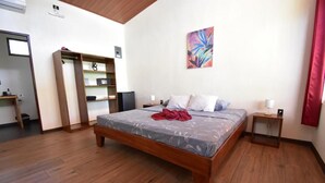 Une chambre à coucher avec un lit, une armoire, une table de chevet et un tableau accroché au mur.