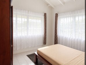 A bedroom with a bed, curtains, and a window. - Maison Teranga- 70m2, 2-BRM apartment, with AC, 5 minutes drive to Rodney Bay (Gros Islet)
