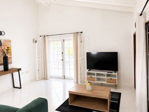 A modern living room with a flat-screen TV, a wooden coffee table, and a green sofa. - Maison Teranga- 70m2, 2-BRM apartment, with AC, 5 minutes drive to Rodney Bay (Gros Islet)