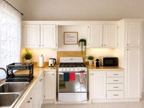 A kitchen with white cabinets, a stove, a microwave, and a sink. - Maison Teranga- 70m2, 2-BRM apartment, with AC, 5 minutes drive to Rodney Bay (Gros Islet)