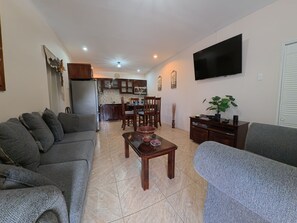 A living room with a sofa, a coffee table, and a TV mounted on the wall. - Sweet Escape Welcoming  2-bedroom apartment  Kelly Village with AC comfort (Kelly Village)