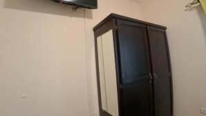 Ein Zimmer mit einem Wand-Fernseher, einem dunklen Holzschrank und einem gemusterten Teppich.