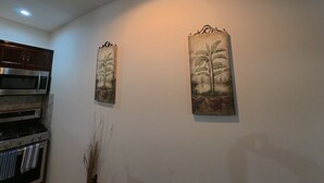 Eine Küche mit Mikrowelle, Backofen und Schränken. Zwei an der Wand befestigte Pflanzenbilder.
