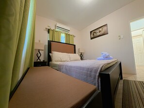 Hotelkamer met een bed, nachtkastje met een lamp, een wandairco en een deur.