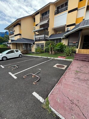A multi-story residential building with a parking lot in front.