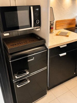 A compact kitchen with a microwave, a coffee machine, and a built-in oven.