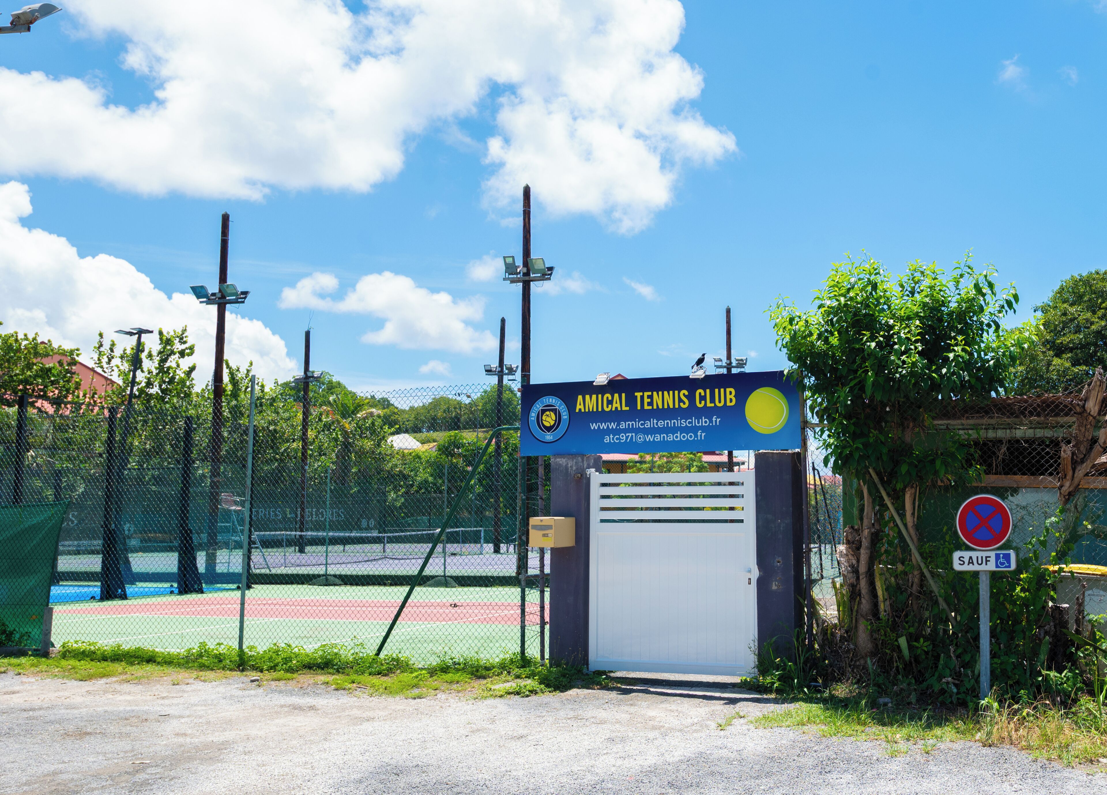 A tennis court with a sign for the Amical Tennis Club.