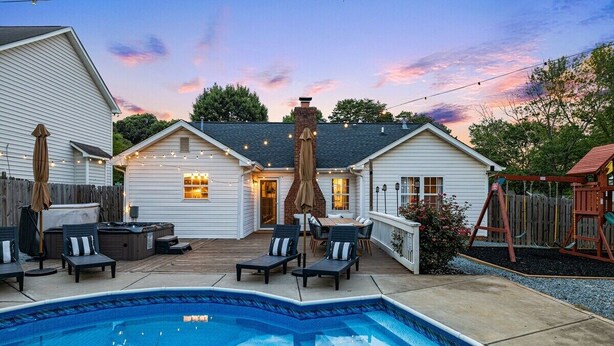 Ein Garten mit Schwimmbad, Gartenmöbeln und einer Holzterrasse.