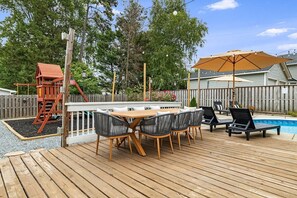A wooden deck with a pool table, chairs, and a swing set. - 4BR Backyard Oasis: Pool, Hot Tub & Fire Pit (Charlotte)