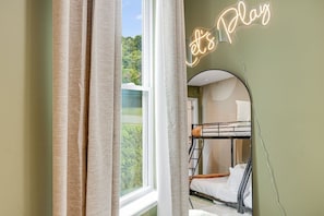 A bunk bed room with a neon sign reading 'Let's Play' and a window with curtains. - 4BR Backyard Oasis: Pool, Hot Tub & Fire Pit (Charlotte)