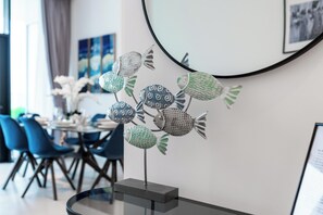 A modern dining area with a round table, chairs, and a decorative fish sculpture. - bnbme - Marquise Square Tower - 2BR (Dubai)