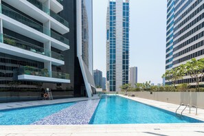 Een modern gebouw met een zwembadgedeelte, inclusief een zwembad met helderblauw water en een betegeld zonnedek.