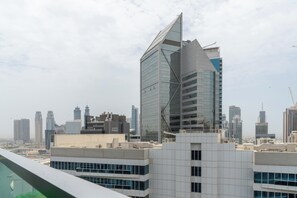 A modern high-rise building with a unique angular design, surrounded by other skyscrapers in a cityscape. - bnbme - Marquise Square Tower - 2BR (Dubai)
